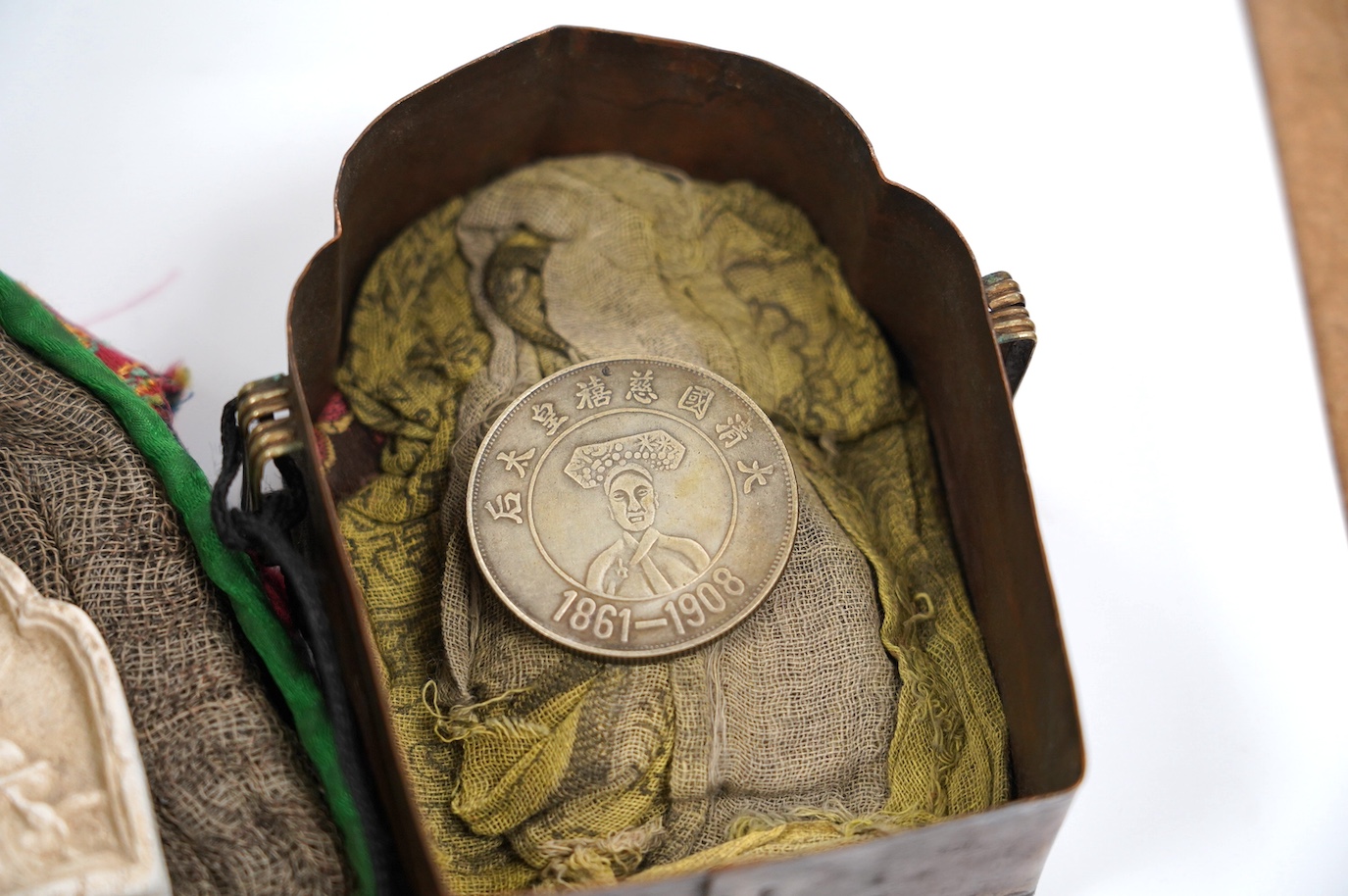 A Tibetan repoussé white metal and copper travelling shrine in a quilted cloth case, 10.5cm high. Condition - fair